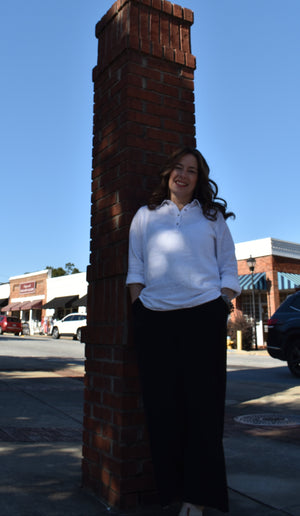 Christina standing next to a brick column with a streetlight against a blue sky.