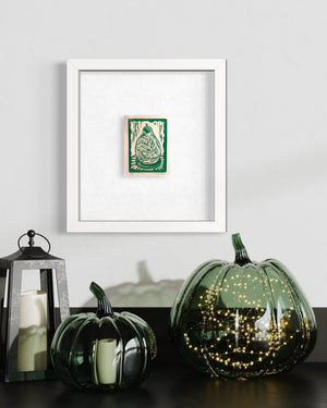 Decorative pumpkins on a black surface with a framed picture on a white wall.